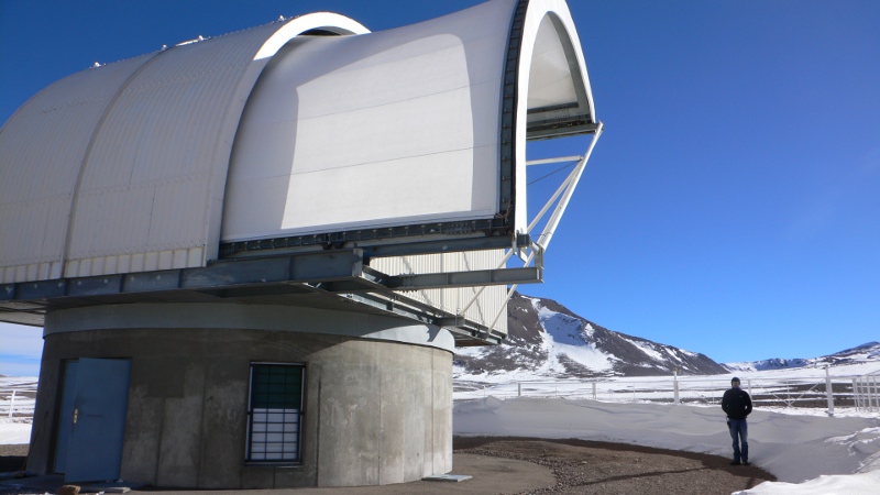 Picture of Ronan Higgins standing next to NANTEN telescope